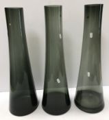 A set of three smoked glass tall vases of tapering form bearing labels to underside 