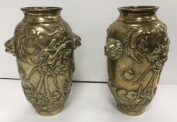 A pair of Chinese bronze relief work dragon decorated vases with lion mask handles raised on a
