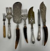 A collection of various antler and silver handled serving knives and forks,