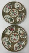 A pair of Chinese famille rose plates set with floral decorated panels on a green and pink ground