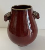 A Chinese sang de boeuf baluster shaped vase with stag's head handles,