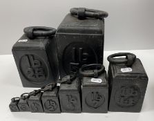 A graduated set of nine black painted cast iron ring weights including 56 lb, 28 lb, 14 lb, 7 lb,
