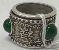 A Chinese white metal and cabochon stone set archer's ring depicting Chinese characters,
