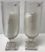A pair of cut glass hurricane style lamps raised in square pedestal bases,