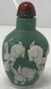 A Chinese green glass snuff bottle with white cameo cut style decoration of dragon and rabbits,