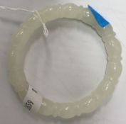 A carved white jade bangle of beaded form,