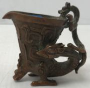 A Chinese bronze libation style cup ornament, the cup with scrolling decoration,