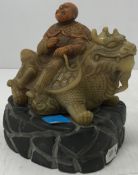 A carved stone seal of sage on the back of a dragon, bears mark to base, on a resin stand,