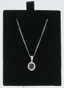 An 18ct white gold cluster style pendant with central oval sapphire approx. 0.26ct surrounded by