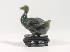 A 20th century spinach jade figure of a duck, carved standing with its head turned to one side,