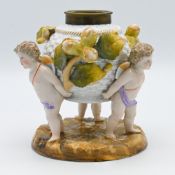 A 19th century German porcelain group with three winged cherubs carrying oil lamp base, underglaze