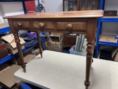 A Victorian side table fitted with three drawers on turned legs.