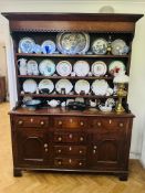 A Georgian oak two part dresser with a shelf upper section and a base with six drawers and two