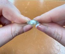 A platinum ring set with a single pearl and diamonds, size O