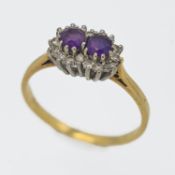 An 18ct yellow and white gold set amethyst and diamond double cluster ring, size S.