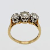An 18ct yellow gold three stone diamond ring, centering on a round brilliant cut diamond, with