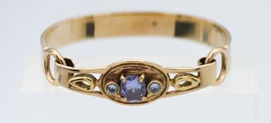 A yellow gold (not hallmarked) heavy gauge hook clasp bangle set with three stones in the centre,