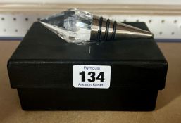 A crystal topped wine stopper with a sail boat image.