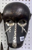 An African Dan monkey mask, carved wood and white metal mounted.
