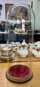 A Victorian tall glass dome with red velvet base.