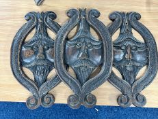Three carved oak wall plaques depicting facial expressions, circa 1900. Height 35cm