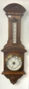 An early 20th century carved oak wall Aneroid Barometer with thermometer, length 102cm.