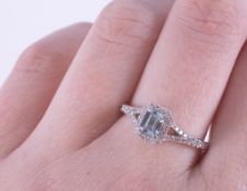 An 18ct white gold ring set with a central emerald cut aquamarine, approx. 0.50 carats, surrounded
