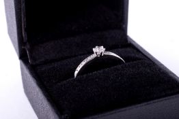 A platinum ring set with a central round brilliant cut diamond, approx. 0.15 carats, with six