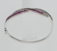 An 18ct white gold ruby and diamond set cross-over bangle.