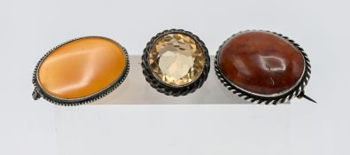 Two white metal and agate brooches, together with a white metal brooch set with a yellow stone. (3)