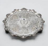 A large silver salver, engraved foliate decoration with shell rim, on three scroll feet,