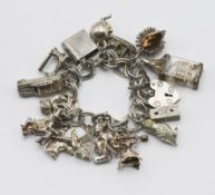 A mainly silver charm bracelet, to include a hedgehog charm, a ship in bottle, a witch, etc.