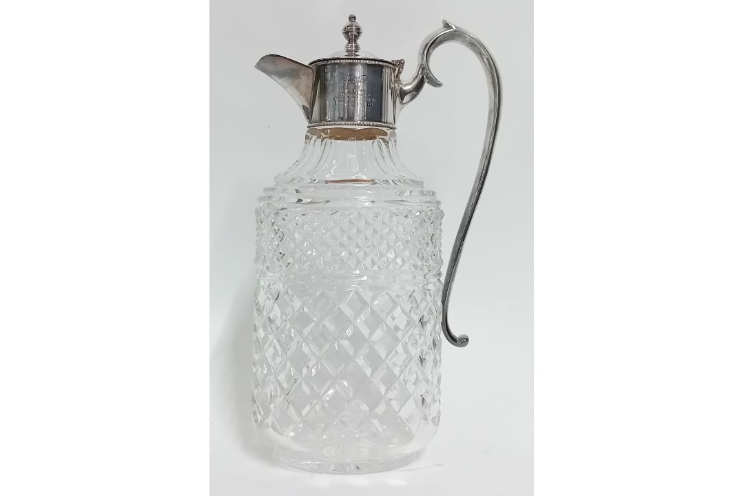 A cut glass and silver plate mounted claret jug with inscription, height 29cm.