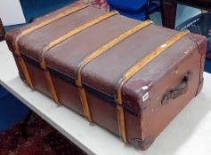 A large brown canvas suitcase, with leather handles and corner reinforcement, and wood banding,