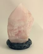 A large piece of pink quartz on a wooden base, height approx 19cm.