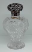 A silver topped cut glass scent bottle, of elaborate embossed foliate design, hallmarked