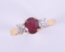 An 18ct yellow gold three stone ring set with a central oval cut ruby, approx.. 0.70 carats with a