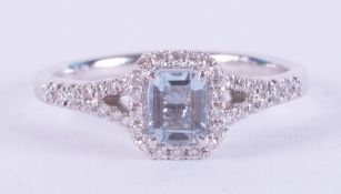 An 18ct white gold ring set with a central emerald cut aquamarine, approx. 0.50 carats, surrounded