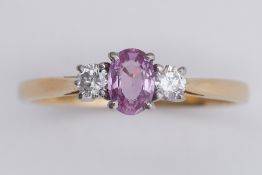 An 18ct yellow & white gold three stone ring set with a central oval cut pink sapphire, approx. 0.36