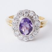 An 18ct yellow & white gold cluster ring set with a central oval cut amethyst, approx. 1.06