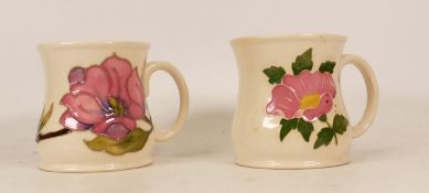 Moorcroft mug of the year 1987 (a/f) and Moorcroft mug decorated with a pink flower (2)