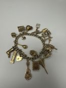 9ct yellow gold charm bracelet hung with 19 x 9ct gold charms to include Well, Concorde, Cello, Gran