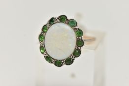 AN OPAL RING, the central opal cabochon within a green gem surround, assessed as green paste,