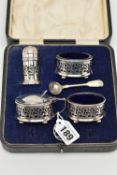 A CASED GEORGE V SILVER FOUR PIECE CRUET SET WITH FOLIATE PIERCED DECORATION, comprising oval