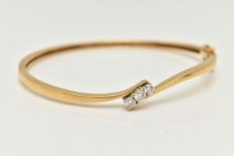 AN 18CT GOLD DIAMOND HINGED BANGLE, a polished bangle of cross over design, set with three round
