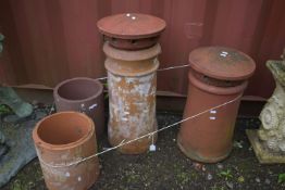 TWO SIZED TERRACOTTA CHIMNEY POTS, with toppers, tallest height 71cm, and two terracotta drain pipes