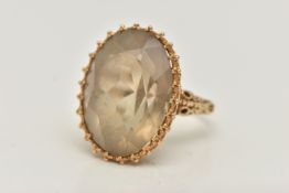 A 9CT GOLD SMOKY QUARTZ DRESS RING, designed as a large oval cut smoky quartz, claw set with applied
