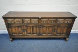 A 20TH CENTURY OAK SIDEBOARD, fitted with four drawers, above four linenfold cupboard doors,