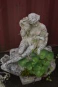 A WEATHERED COMPOSITE GARDEN WATER FEATURE, of a lady sitting on rocks within a shell, holding a