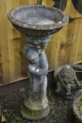 A WEATHERED COMPOSITE BIRD BATH, raised on a putto holding a fish, diameter 46cm x height 98cm (